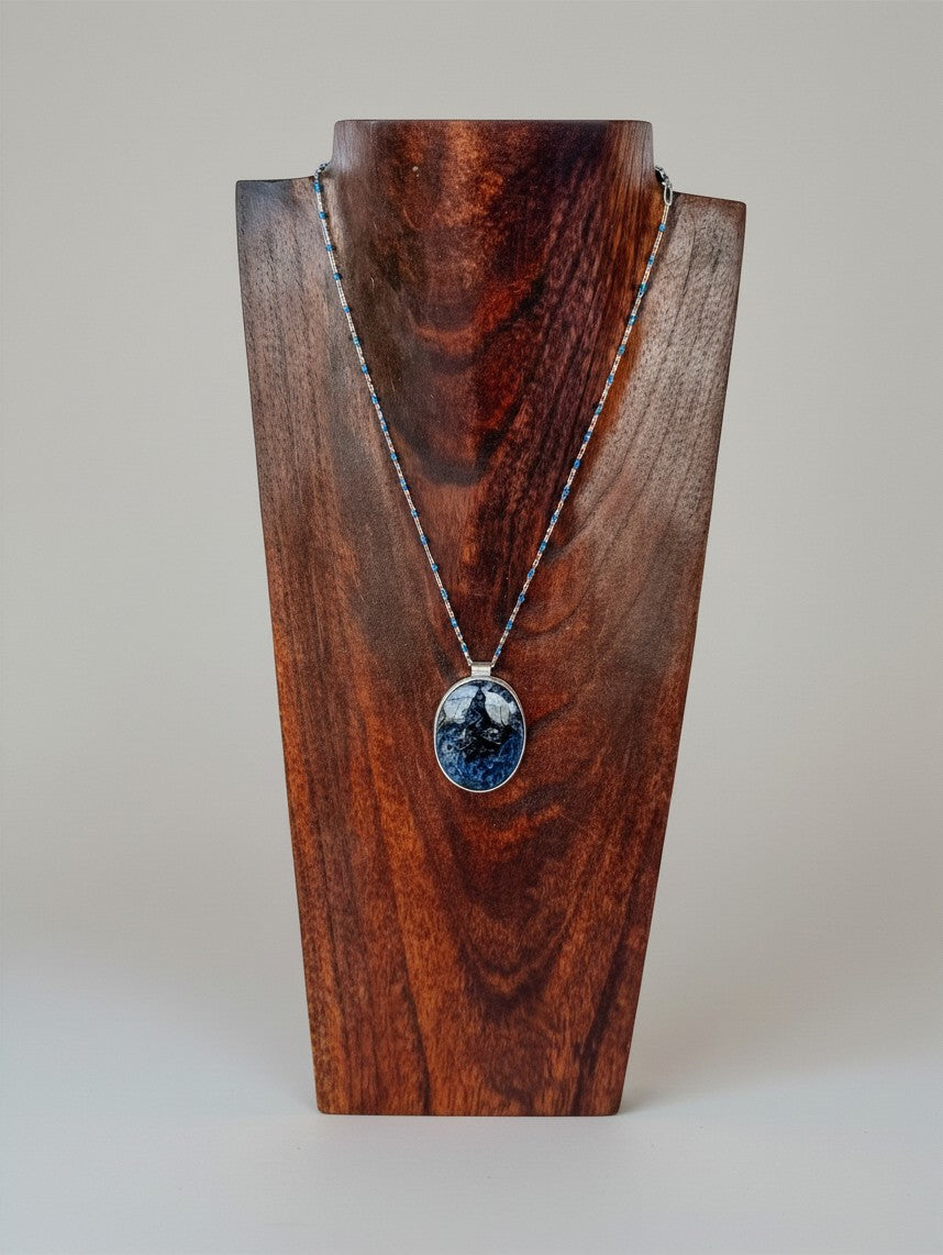 Wooten & Co. Blanco Blue Pietersite necklace with sterling silver setting and blue enamel beads on a wooden display.