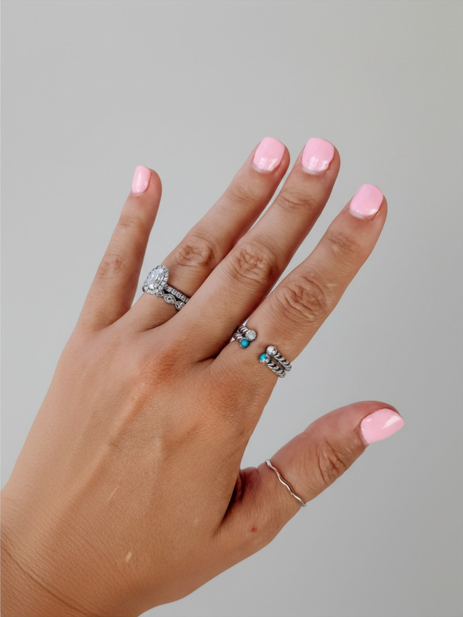 Wooten & Co. Nazareth Turquoise Twist Ring in sterling silver with turquoise stones worn on a hand with pink nails.