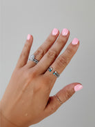 Wooten & Co. Nazareth Turquoise Twist Ring in sterling silver with turquoise stones worn on a hand with pink nails.
