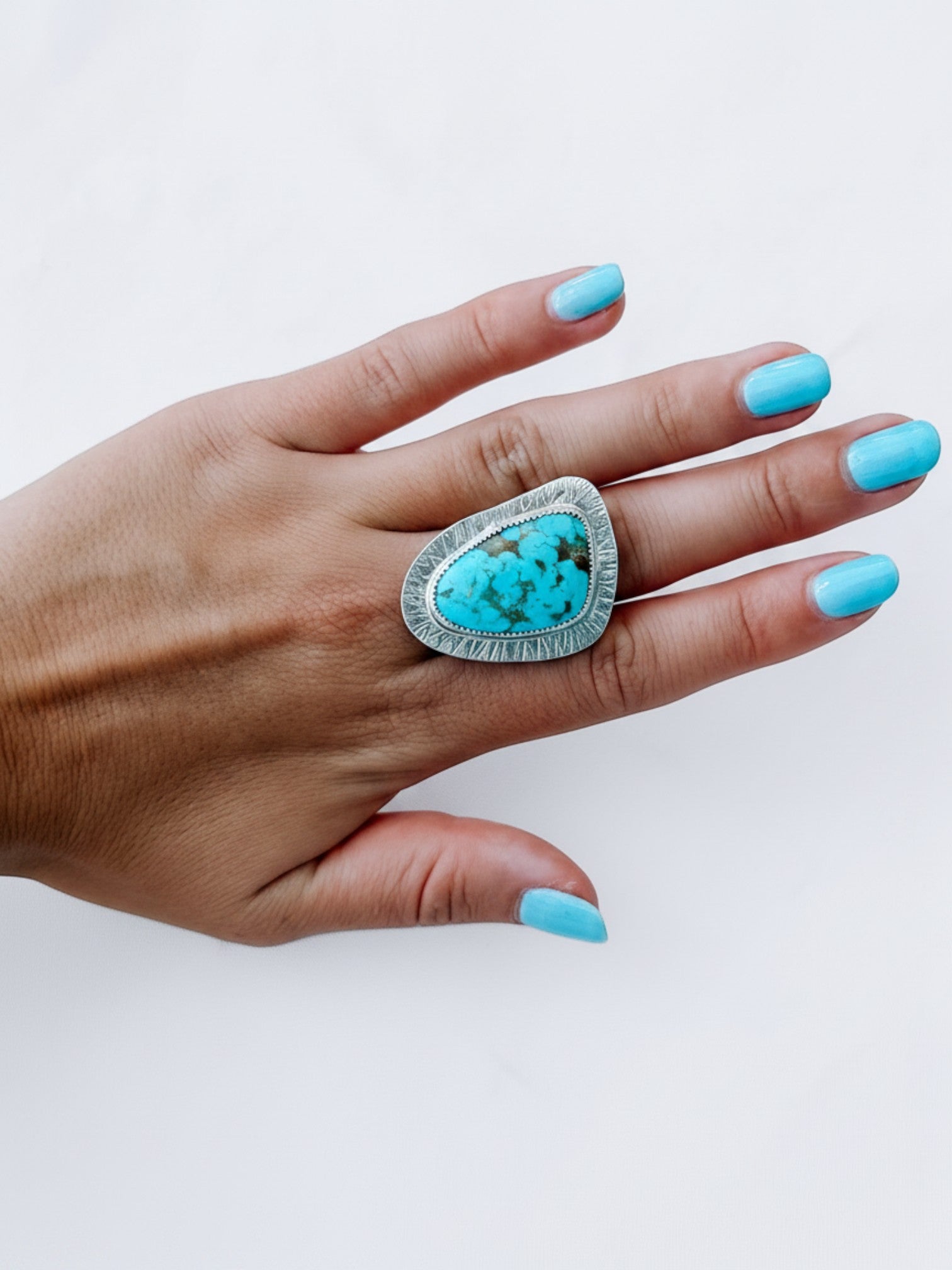 Wooten & Co. Palmer turquoise statement ring in sterling silver with intricate linear texturing worn on a hand