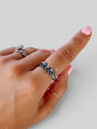 Wooten & Co. sterling silver twist ring featuring two intertwined bands with small turquoise accents on a finger