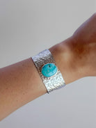 Wooten & Co. Stowell turquoise cuff bracelet featuring a wide hammered sterling silver band on a wrist.